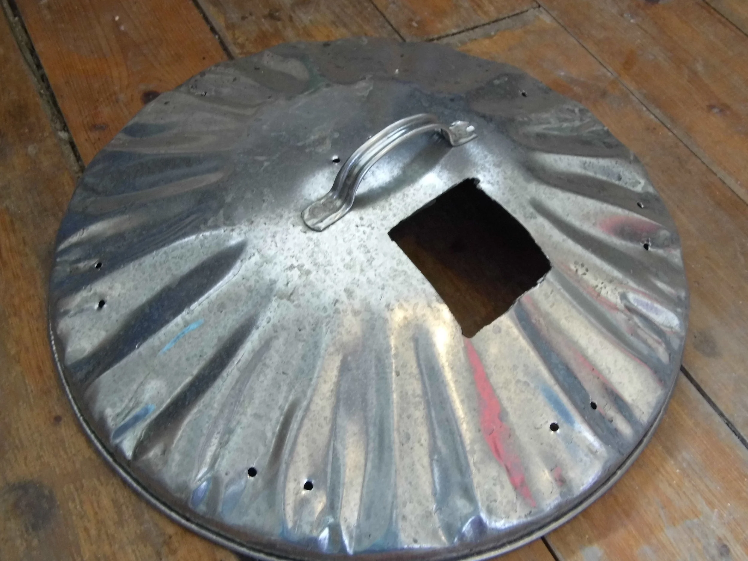 1. A hole is cut in the lid at least 10cm/4inches in diameter. Pairs of holes are drilled at intervals around the edge of the lid and also near the centre.