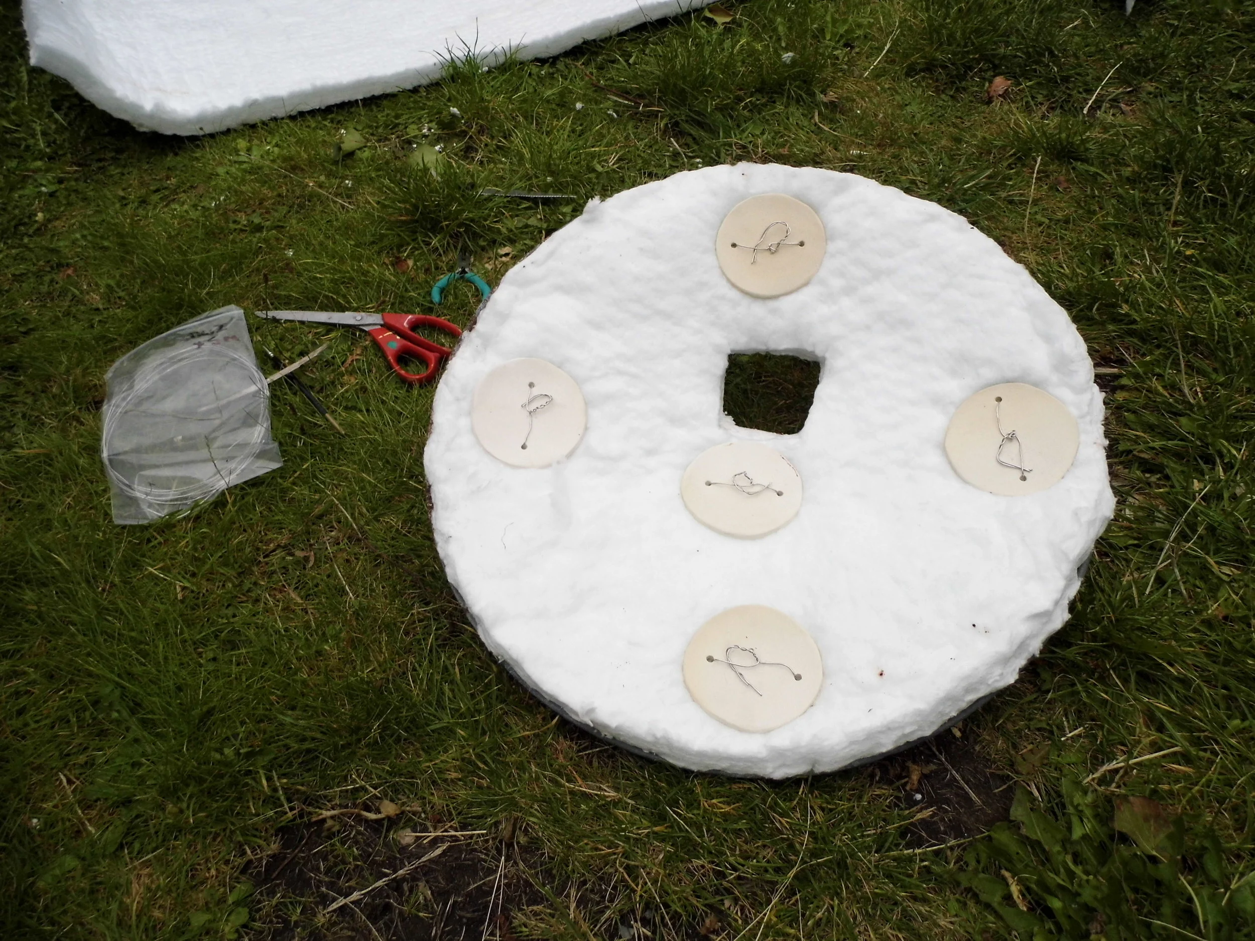4. Pre-made and fired ceramic buttons are wired in place to hold the lining to the lid. Heatproof nichrome wire is used as it can withstand the heat whilst firing the kiln.