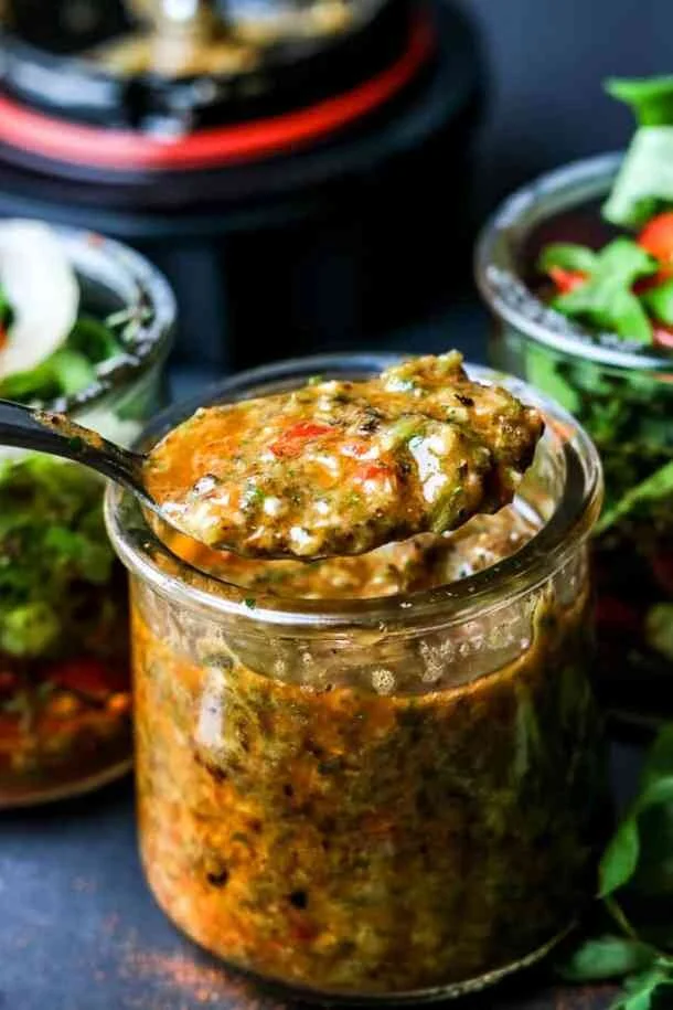 Haitian-Epis-Haitian-Seasoning-Base-Recipe-with-seasoning-lifted-with-spoon-and-seasonings-in-the-background.jpg