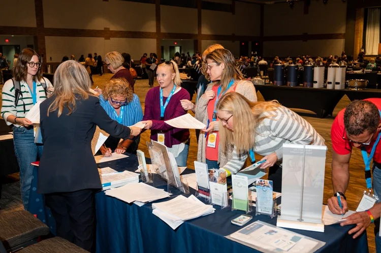 Attendees visit a conference exhibitor table