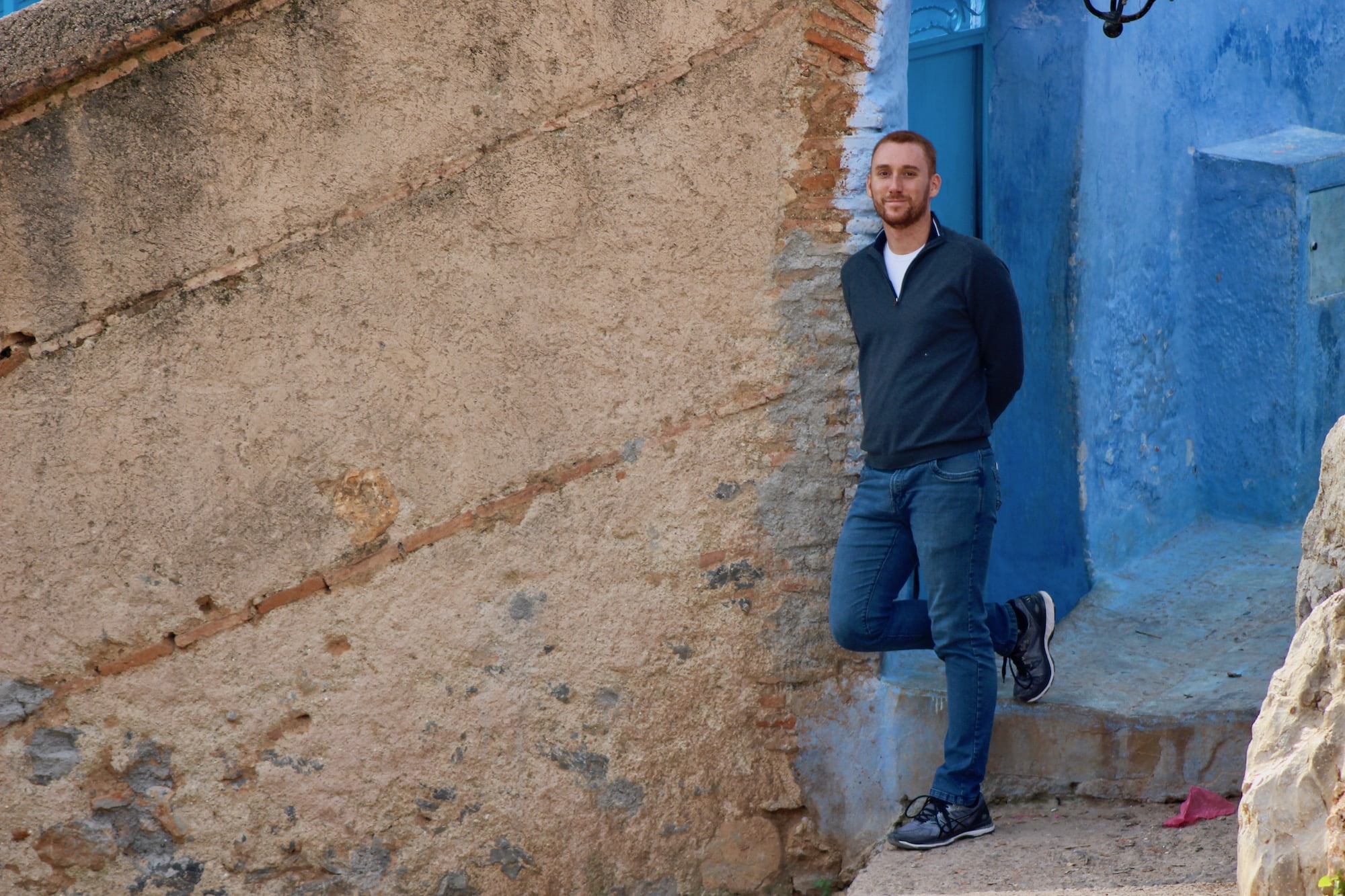 Jordan Aibel standing against a blue wall in Morocco.jpeg