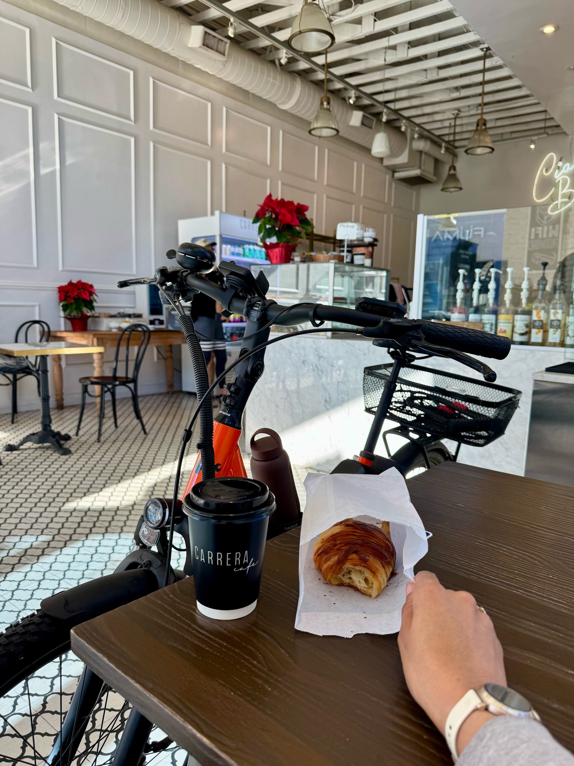 a girl on a bike walks into a coffee shop