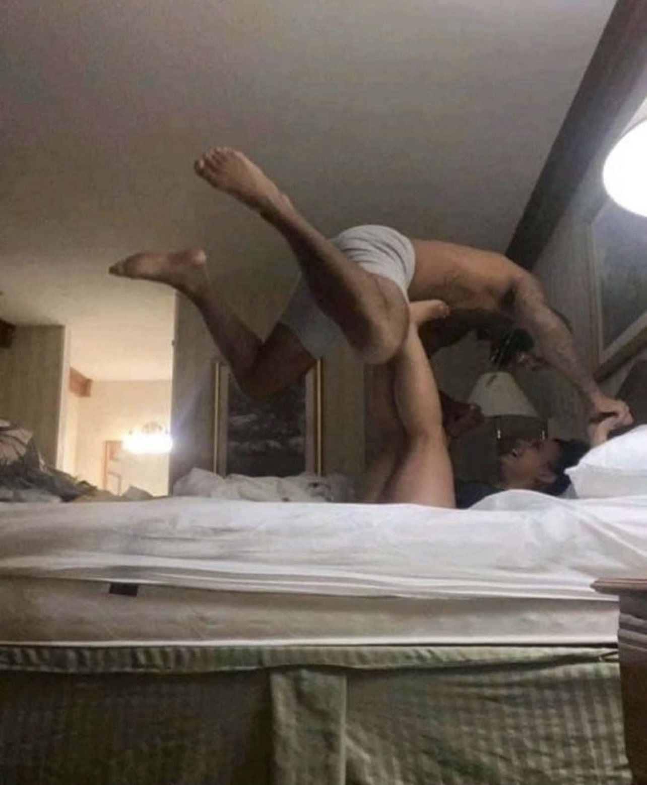 black man and woman playing around in bed laughing