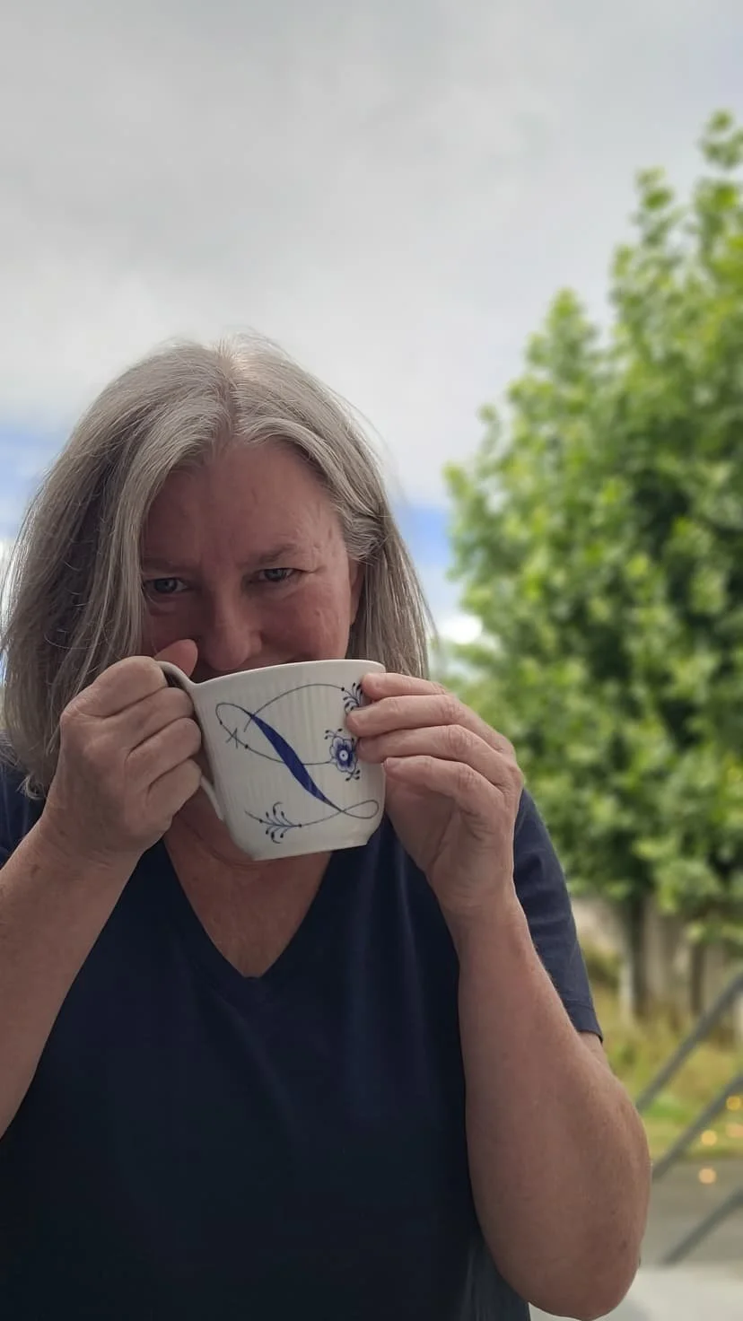 image of lisa smiling micheviously with a cup of coffee held to her face