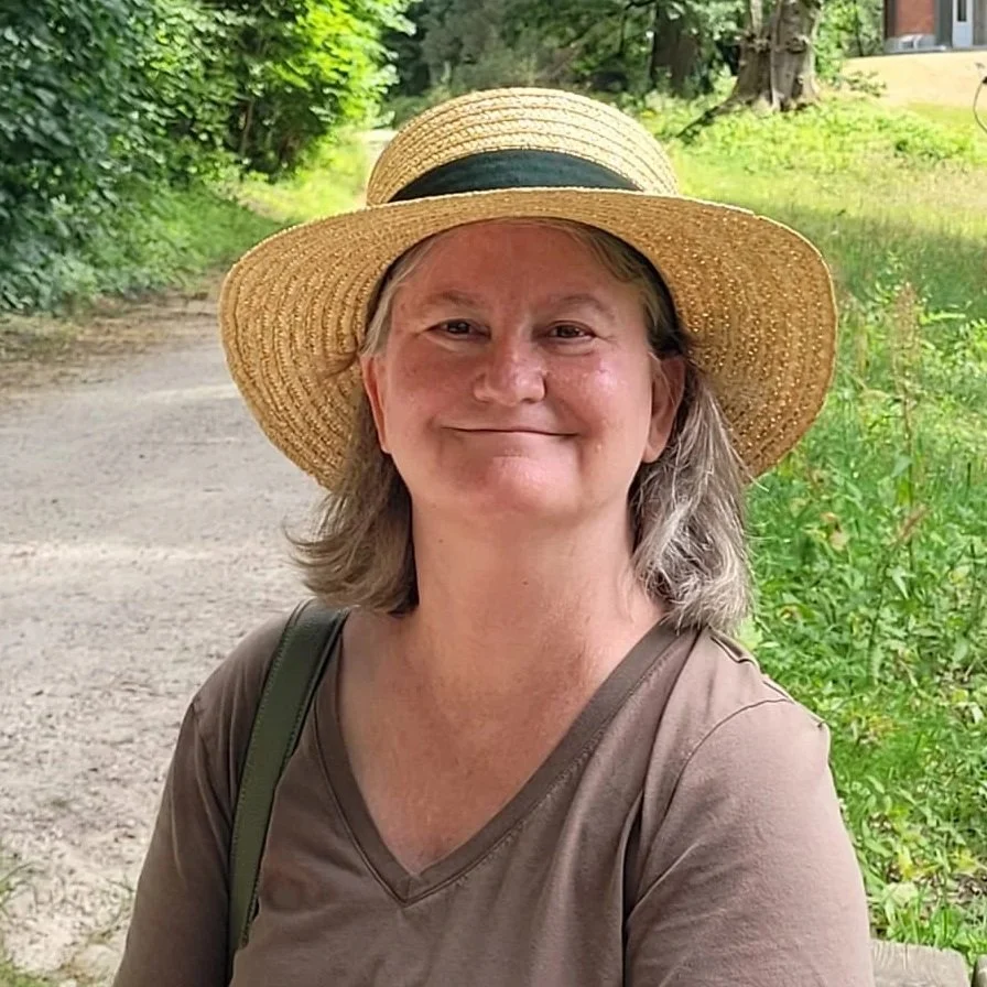 Outdoor portrait of Lisa wearing a brown shirt and a straw hat with a black band