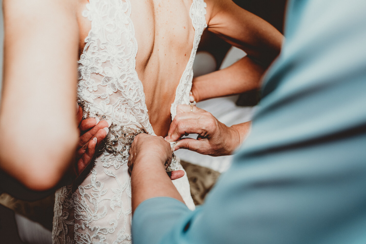 Mum helping daughter zipping up her wedding dress