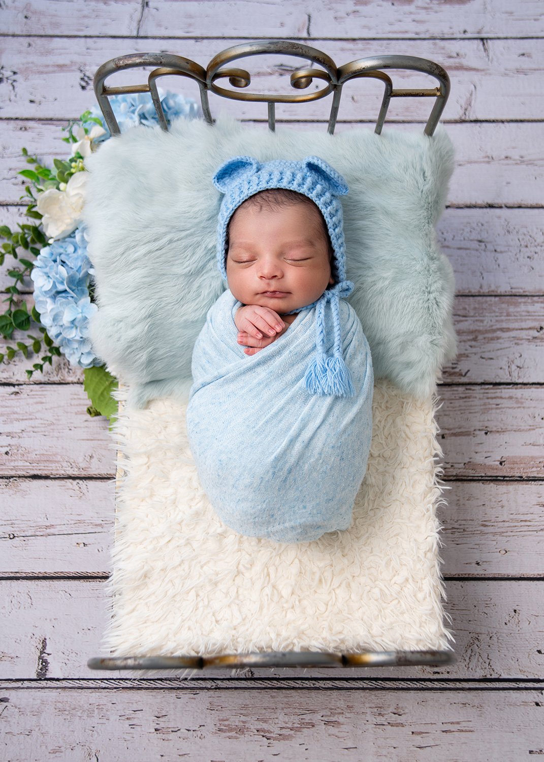 Baby sleeping on tiny bed wearing light blue outfit