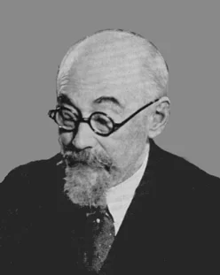 Image Description: Black and White photo of bald man with beard and glasses looking left and down, wearing white shirt with tie and dark jacket, eyebrows raised in interested expression.