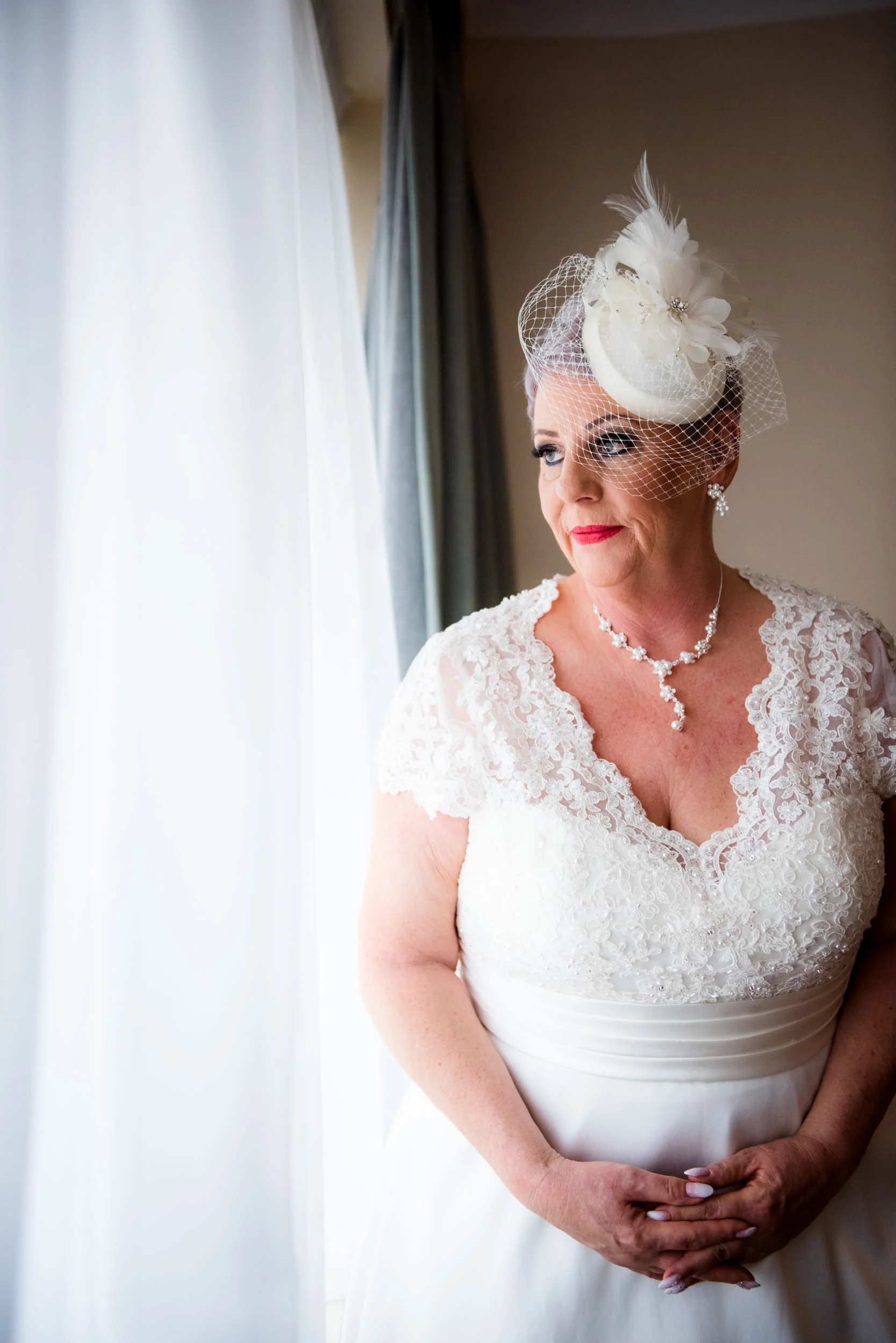 Stunning Bride after putting on the wedding dress looking out of the window