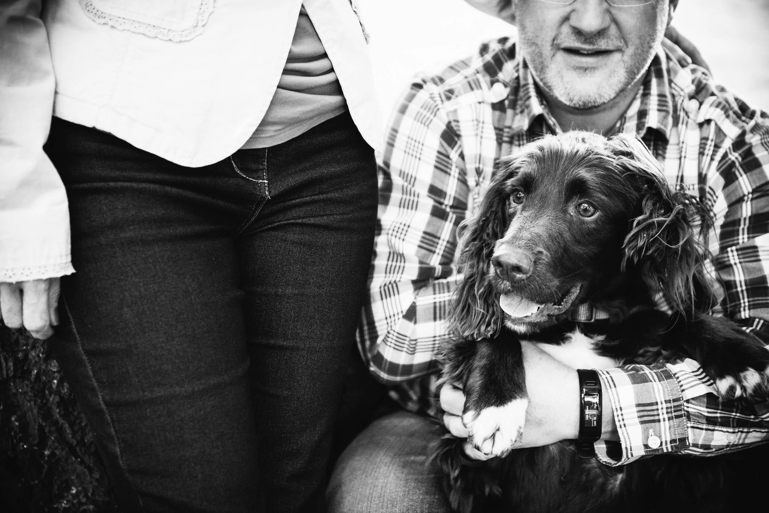 A man holding a black and white dog, both looking happy. The image is in black and white.