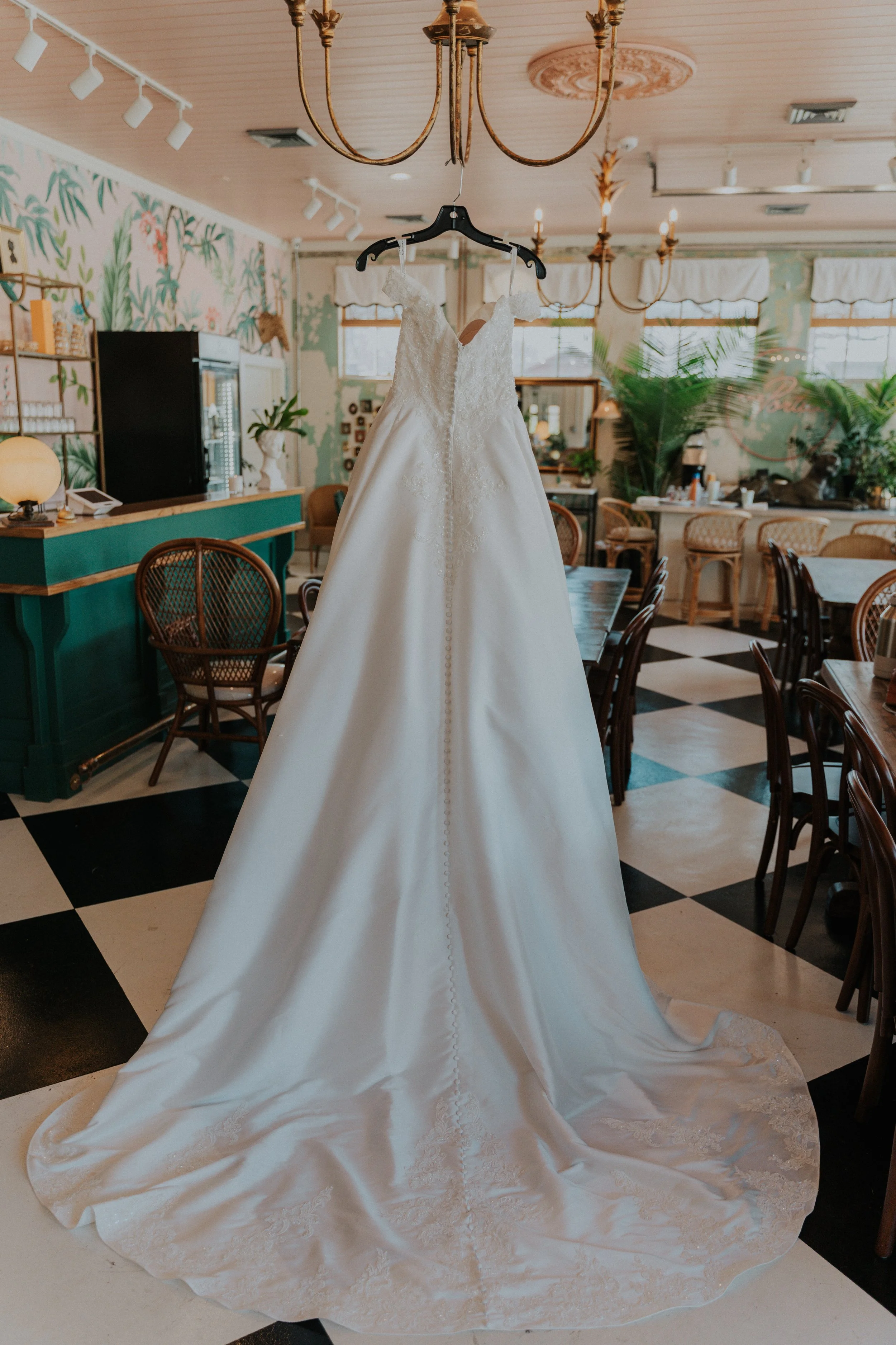 A white wedding dress hanging on a hanger inside a decorated restaurant or cafe.