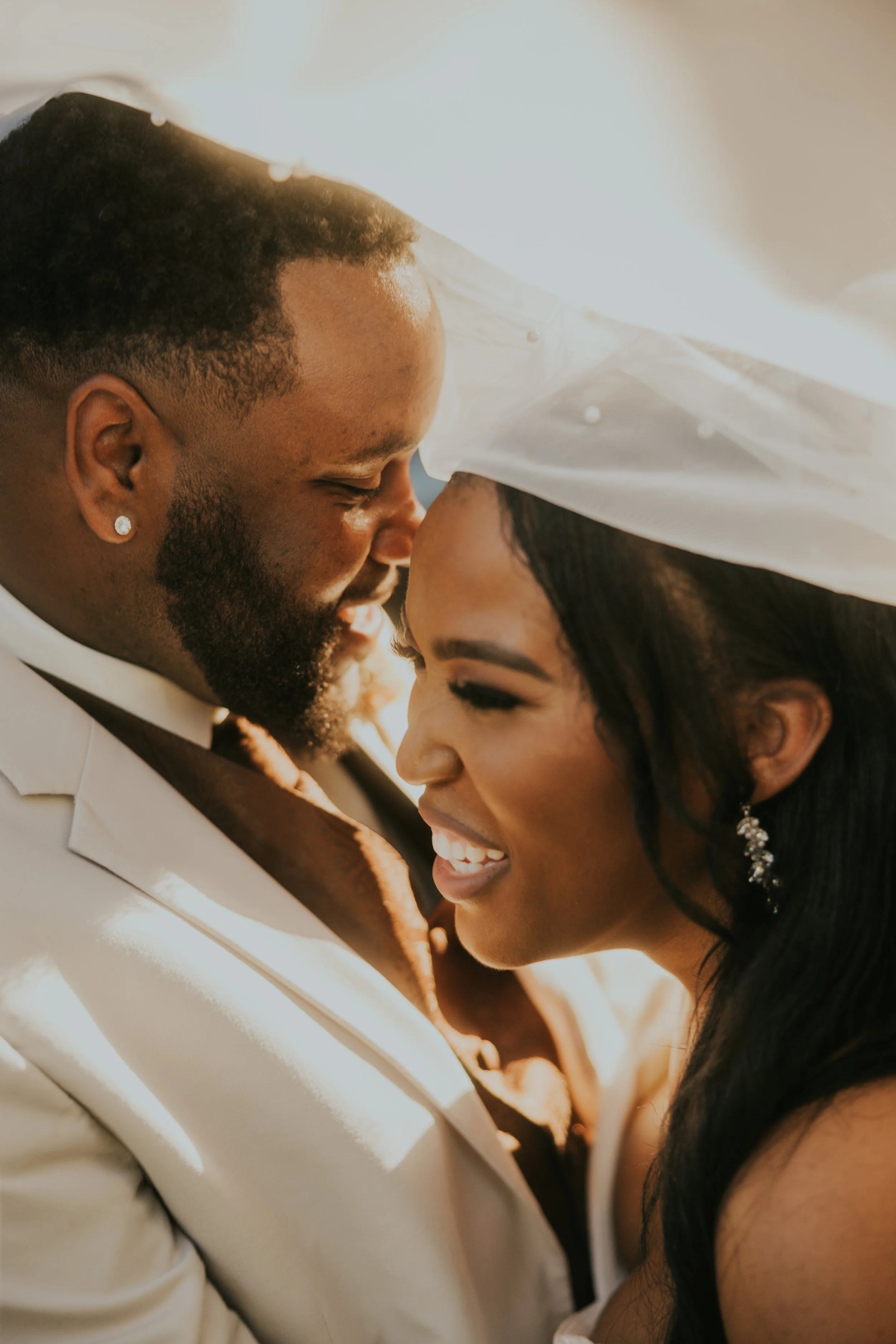 Close-up of a joyful couple gazing at each other, with their foreheads touching, during a wedding or romantic moment.