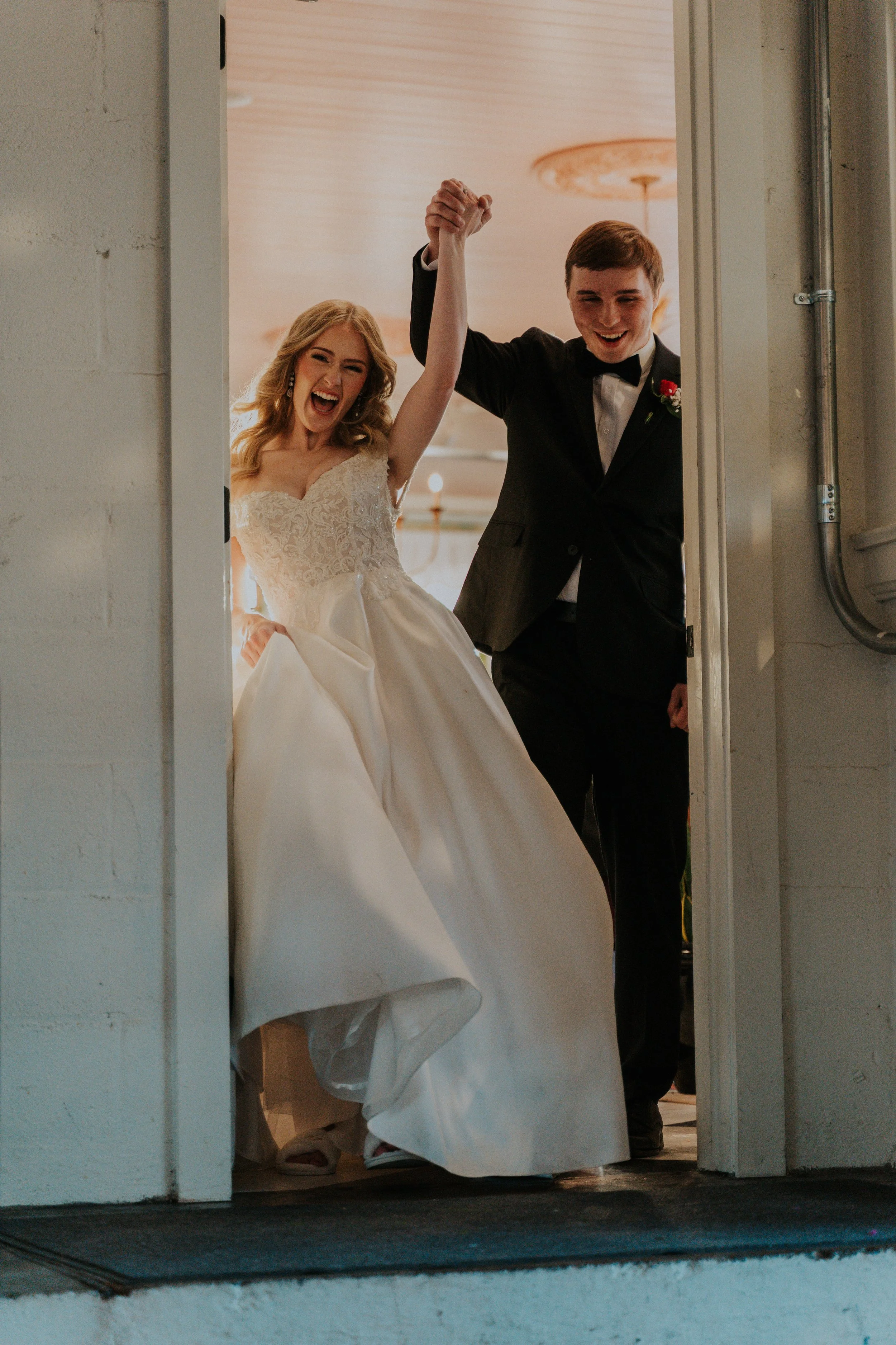 Happy bride and groom holding hands as they enter a room, celebrating their wedding.