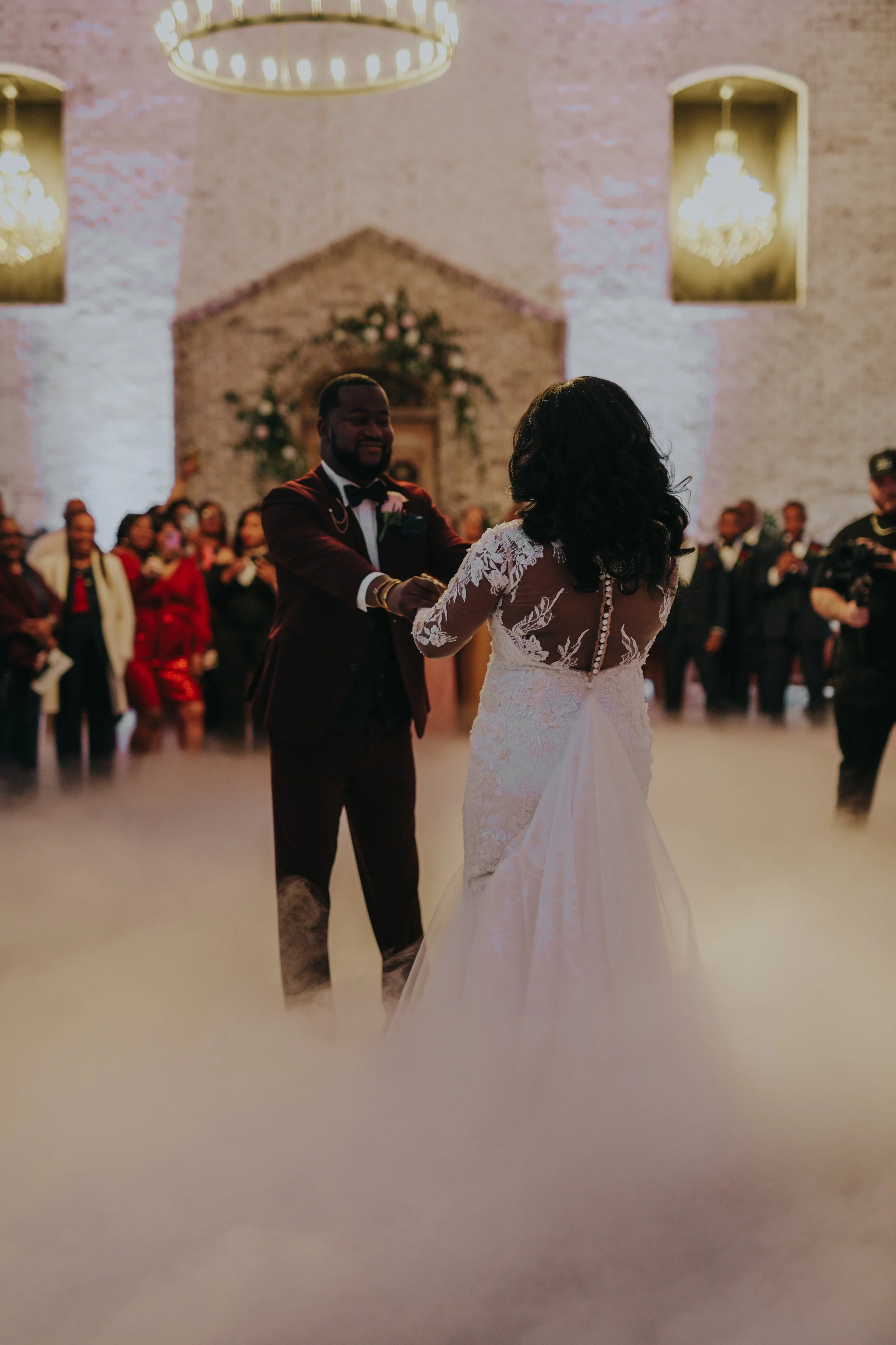 Couple dancing at their wedding reception, with guests and a decorated venue in the background.