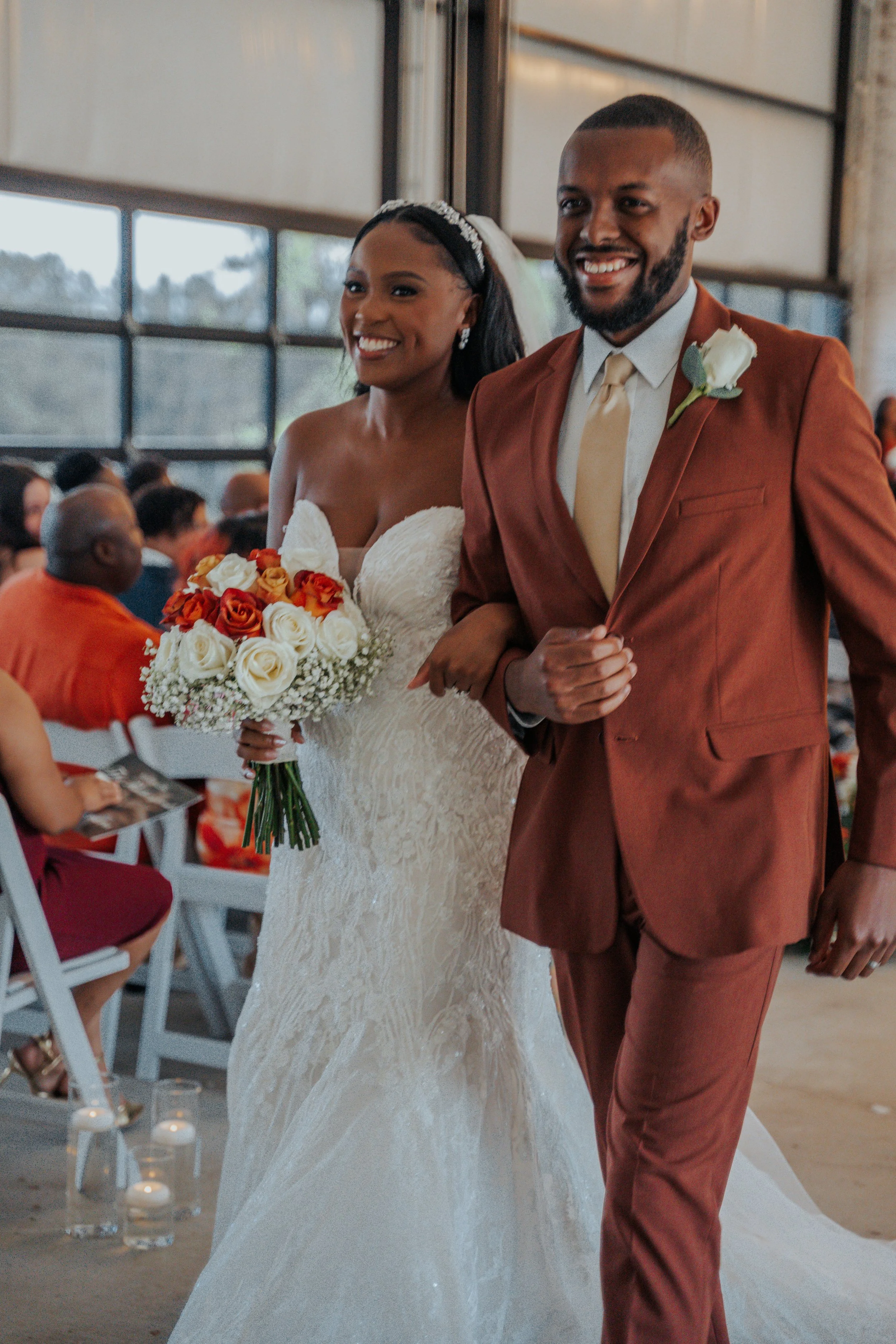 Bride and groom walking down the aisle during their wedding ceremony, with guests seated in the background.