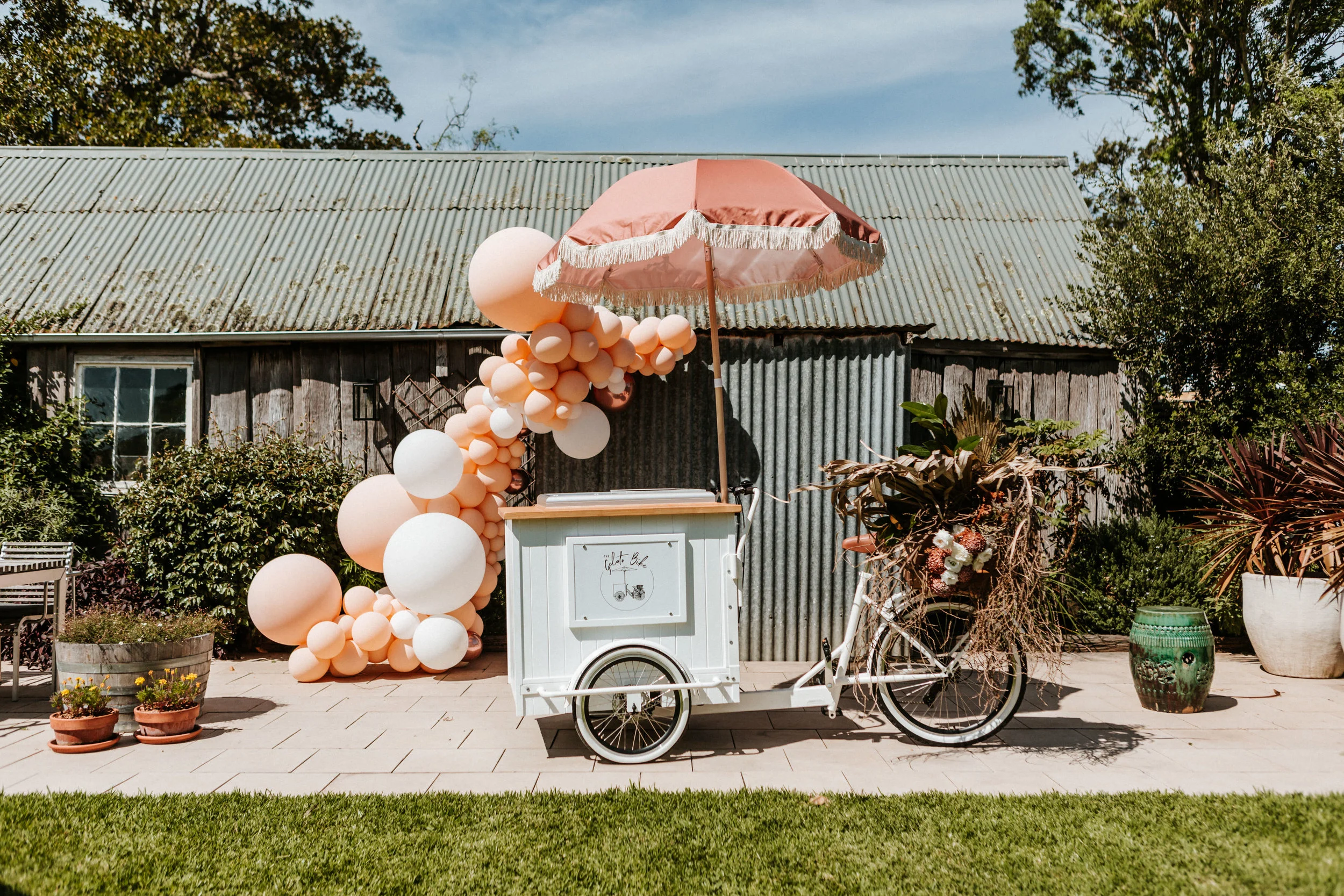 White gelato bike with coral umbrella and balloon styling for weddings and events