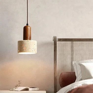 Yellow travertine cylinder pendant light hanging beside a rattan headboard in a minimalist bedroom