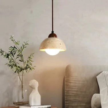 Yellow travertine half-dome pendant light glowing warm white above a bedside table in a neutral bedroom