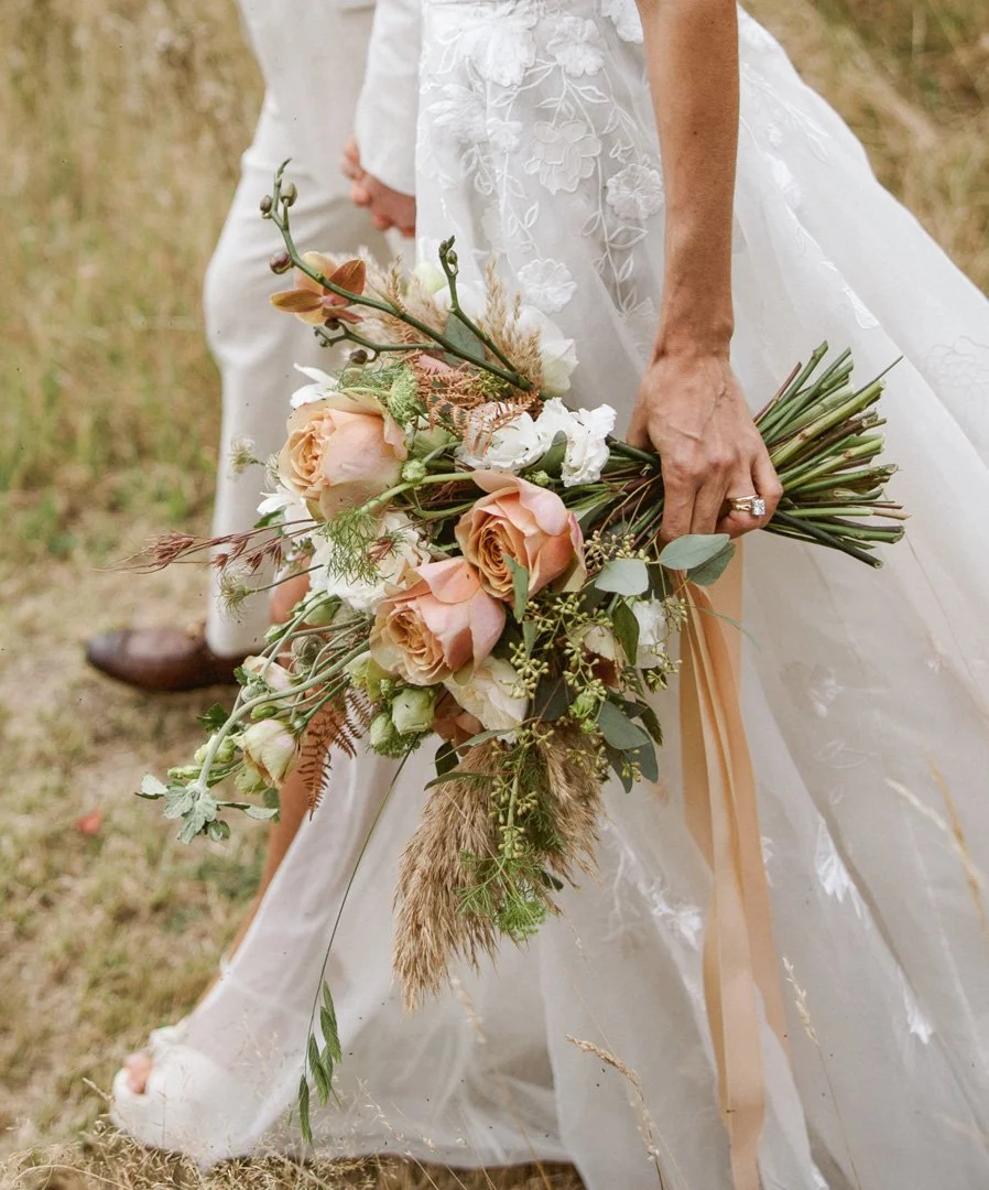 A bride walks with her groom carrying a fresh bouquet of beautiful wedding flowers.