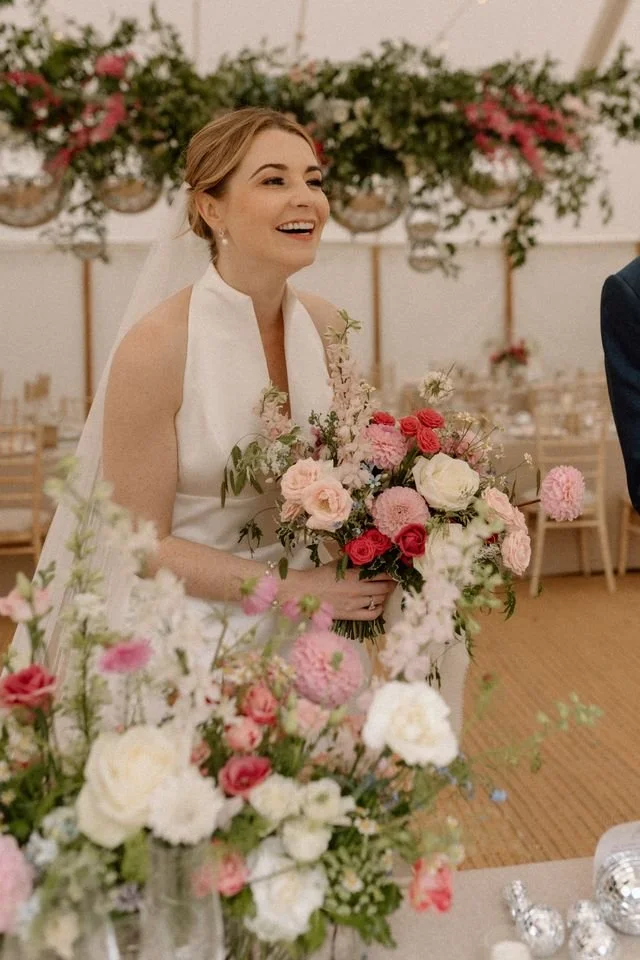 A bride smiles as she holds her bouquet of beautiful wedding flowers.