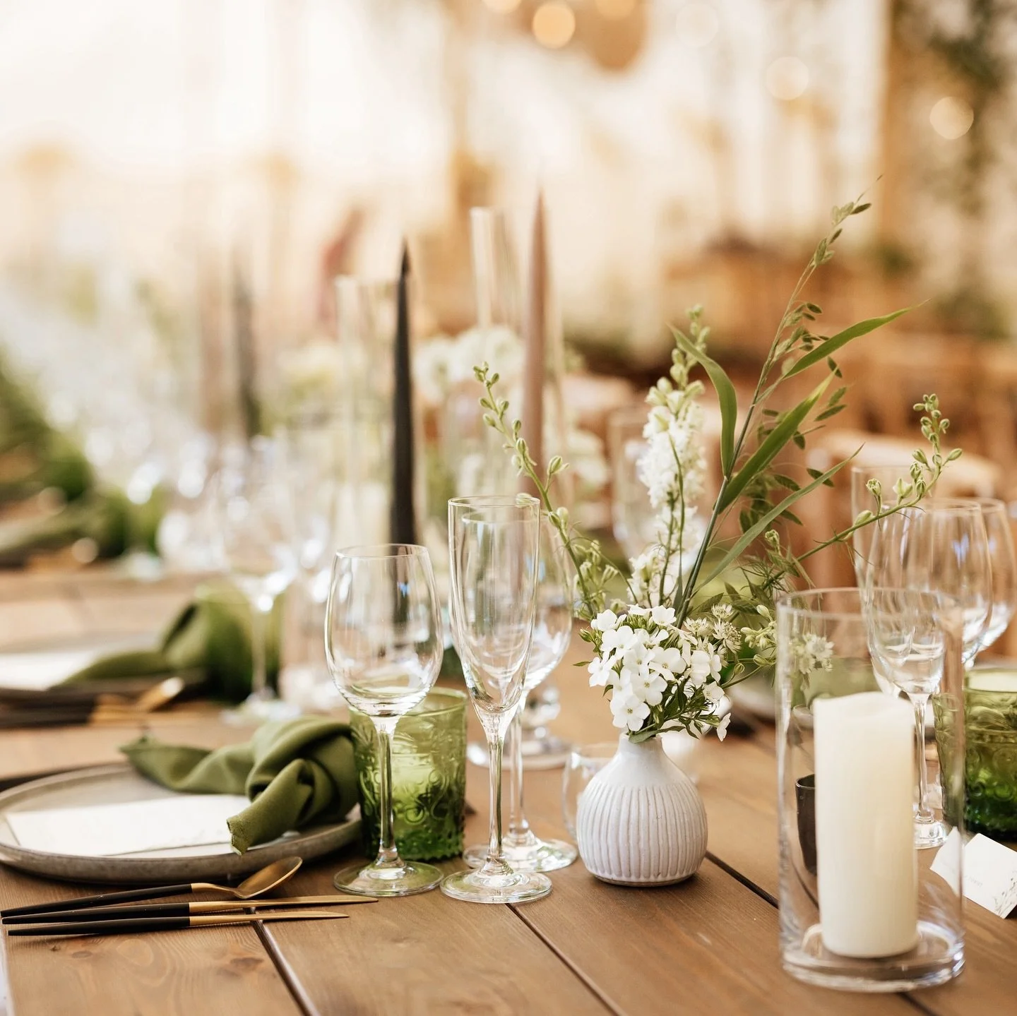 Relaxed summer weddings call for scattered bud vases filled with hedgerow flowers and foliage in frothy whites and sage greens. Add in tonal candles and tableware, a plethora of tall trees and a sunlit marquee and you have the dreamiest reception ven