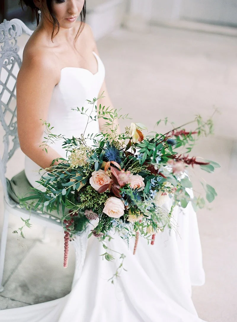 A beautiful Bride sitting on a chair holding her stunning wedding flowers.