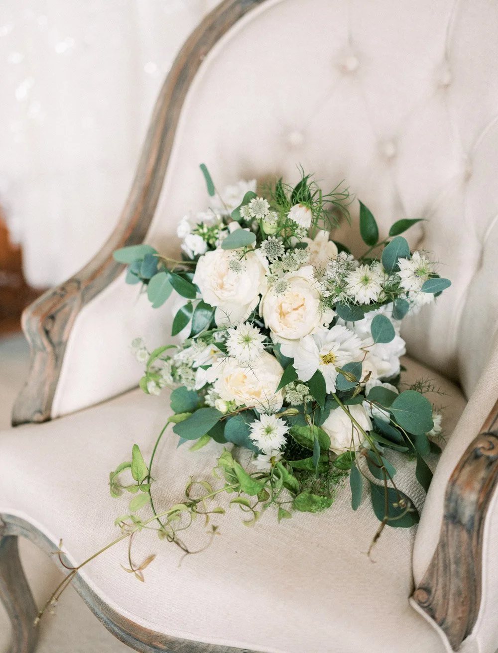 A bouquet of beautiful wedding flowers on a white velvet chair.
