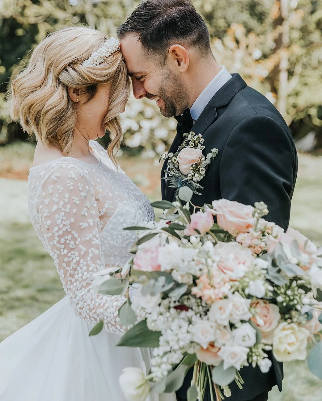 A Bride and Groom stand together with a beautiful bouquet of fresh wedding flowers.