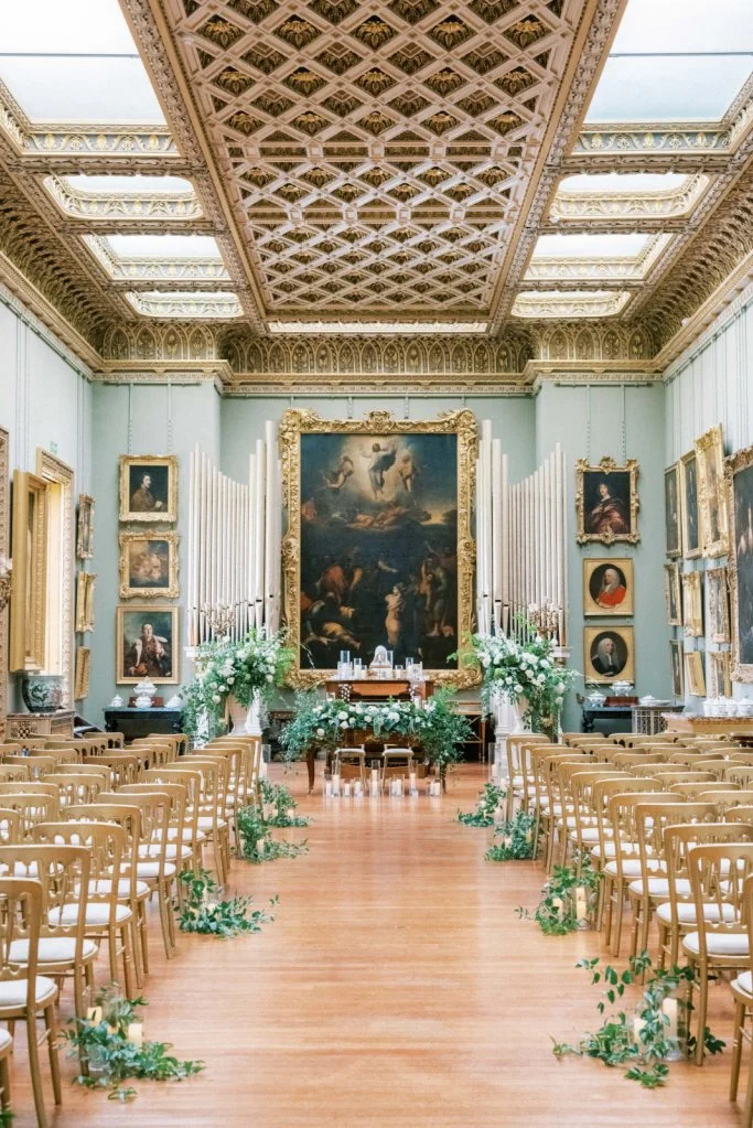 An elegant room decorated with beautiful wedding flowers, and a large portrait painting on the wall.