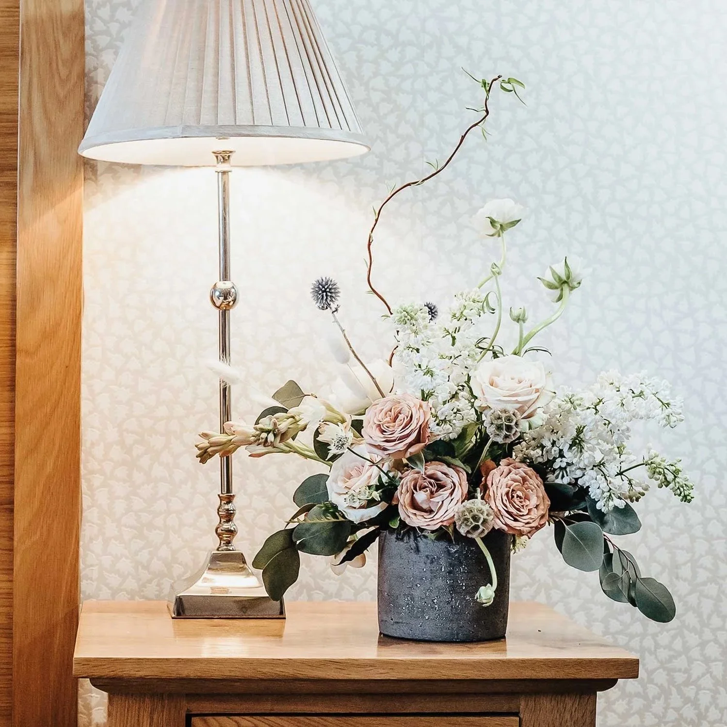 Luxury hotel bedroom styled with elegant floral arrangements and rich tones