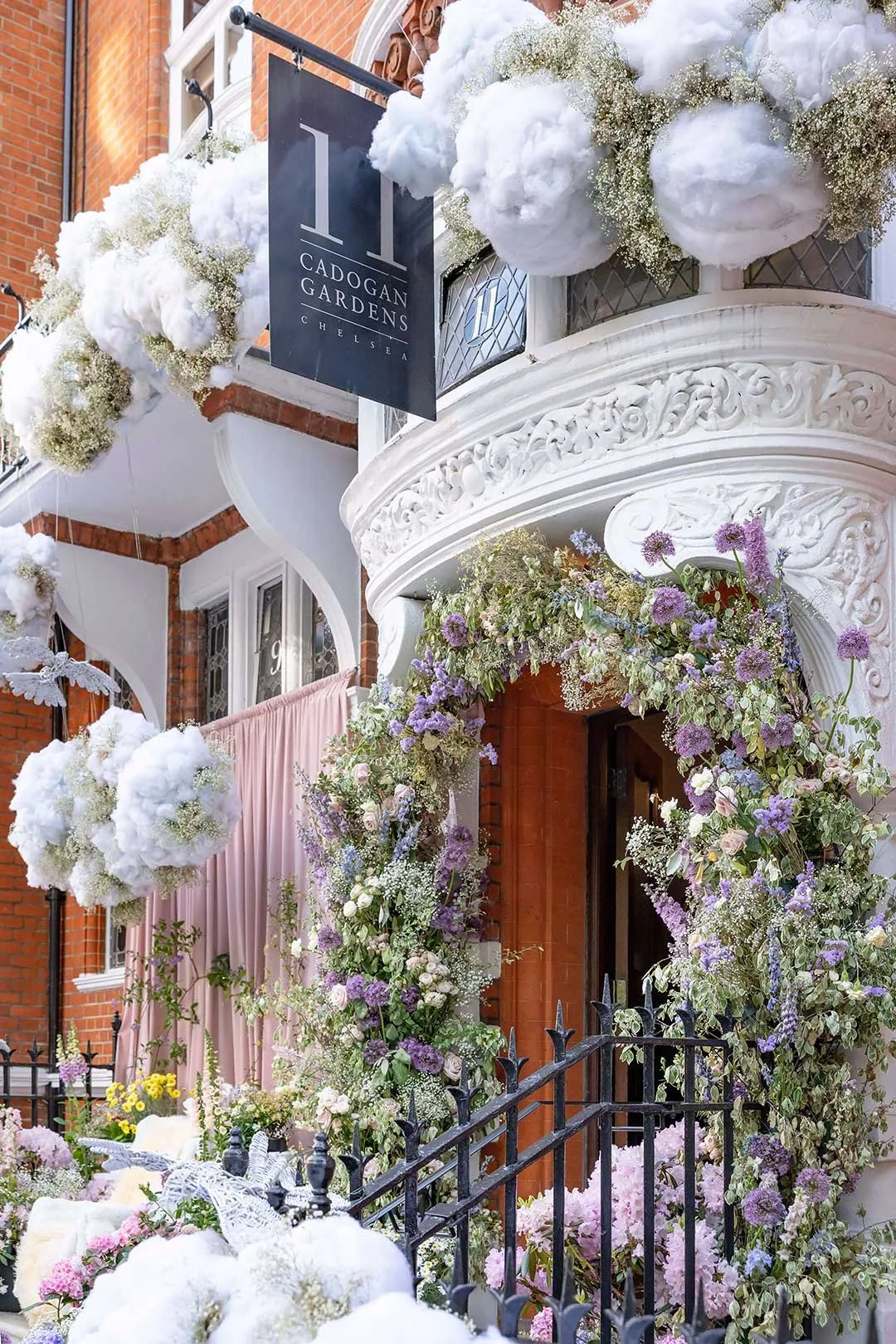 Decorated building entrance with floral arrangements, clouds, and a sign that reads 'Cadogan Gardens Chelsea'.
