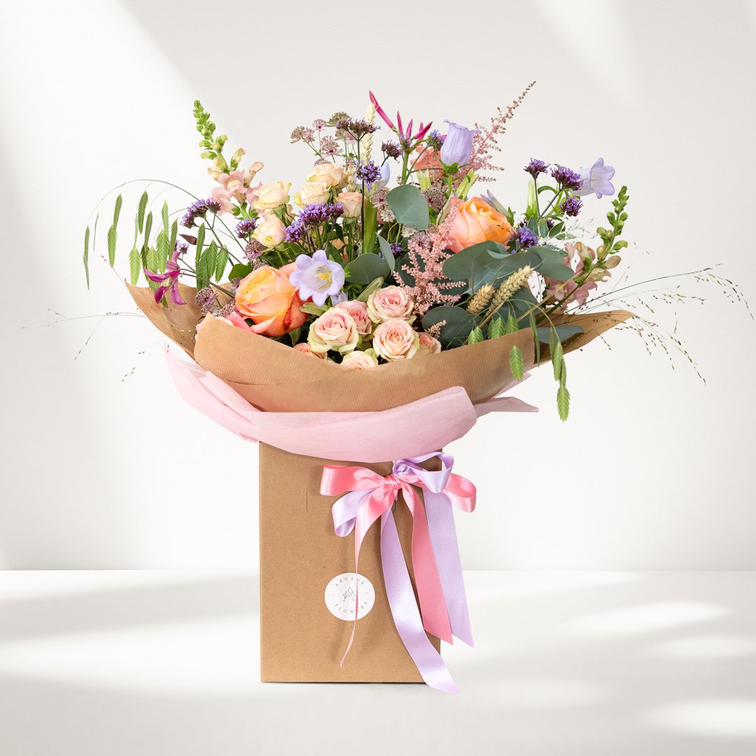 A bouquet of beautiful fresh flowers in a presentation box with ribbons and a gift tag.
