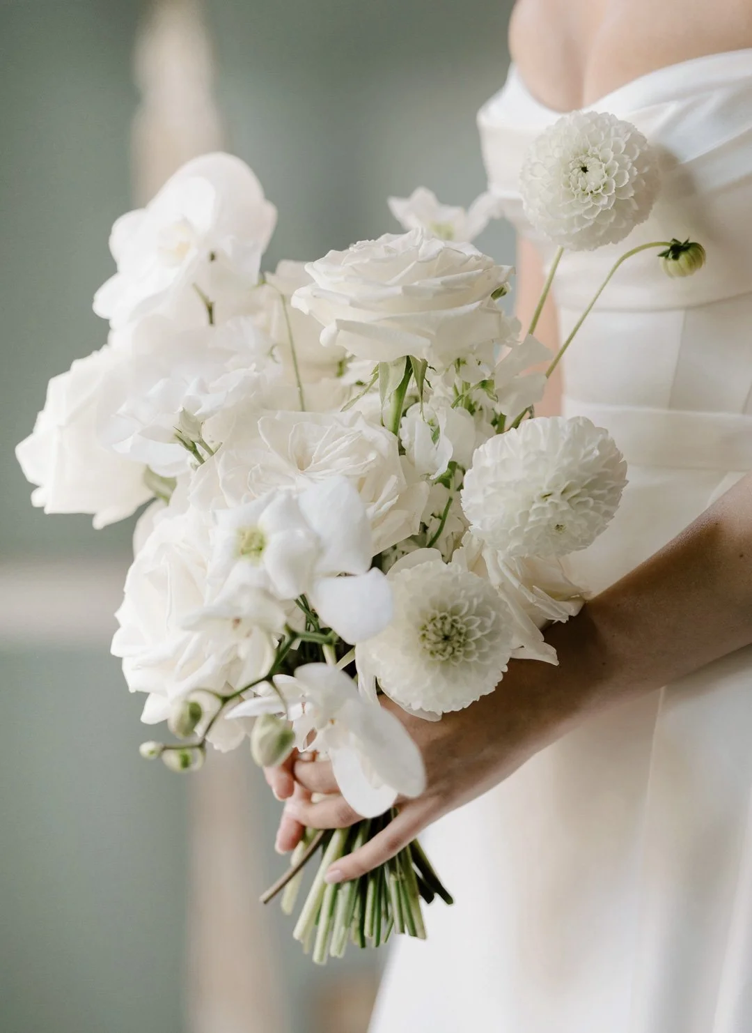 A Bride holds a stunning white bouquet of fresh wedding flowers.