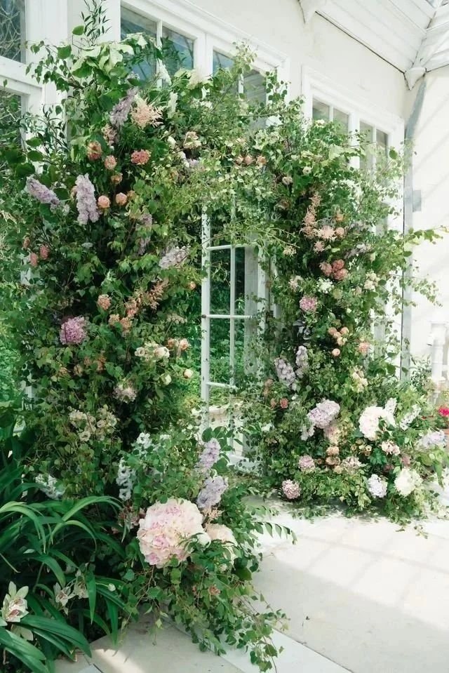 A doorway decorated with a stunning arch of fresh wedding flowers.