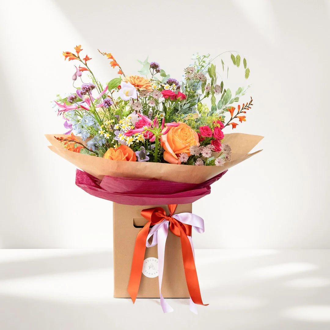 A bouquet of beautiful fresh flowers in a presentation box with ribbons and a gift tag.