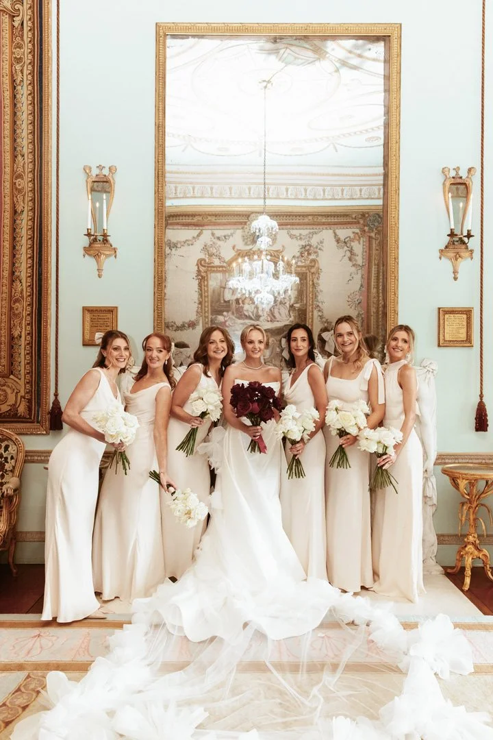 A Bride and her Bridesmaids stand together holding their gorgeous wedding flowers.
