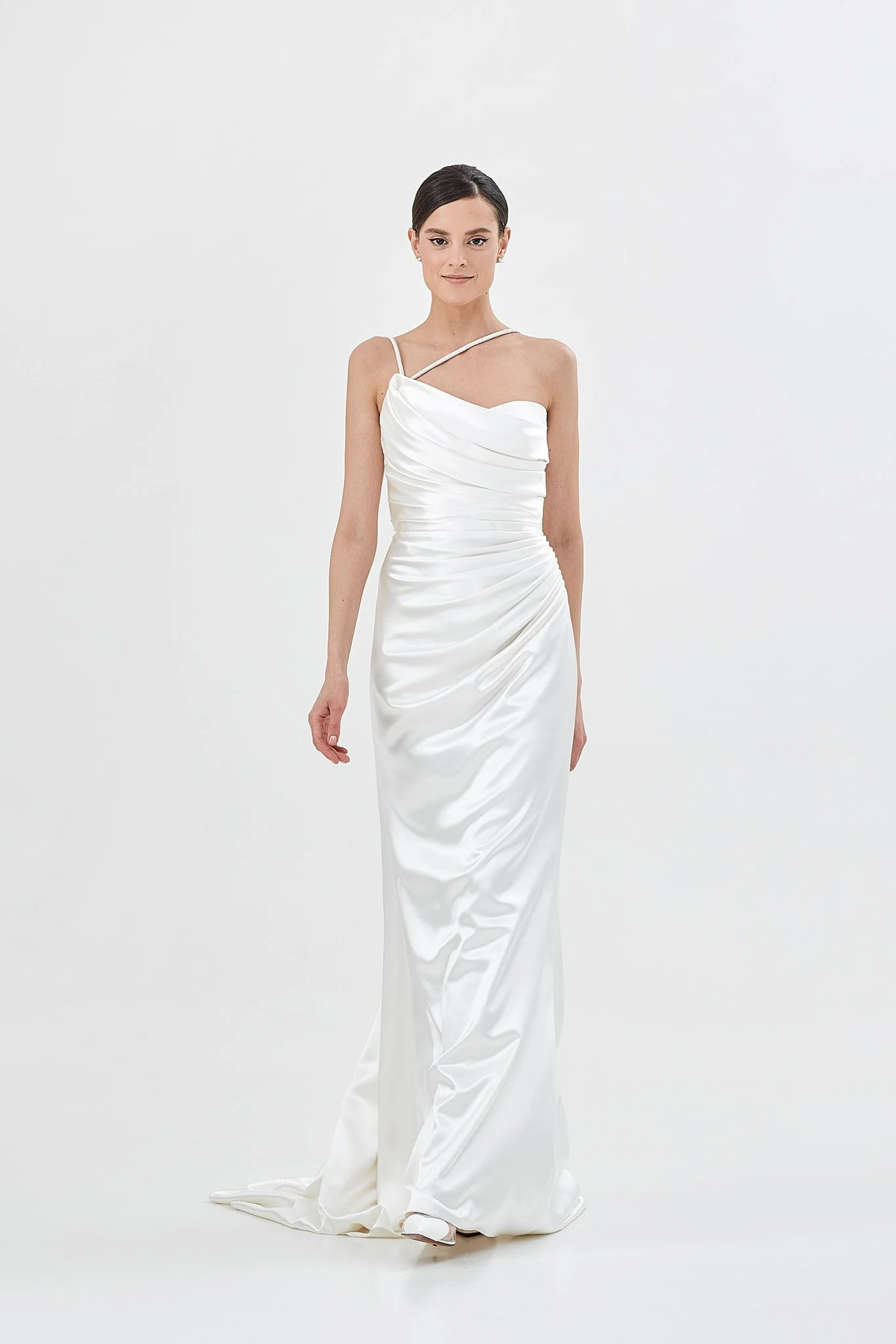 Woman wears strapless wedding dress made from bias cut silk satin with draped corset and skirt in a white photo studio