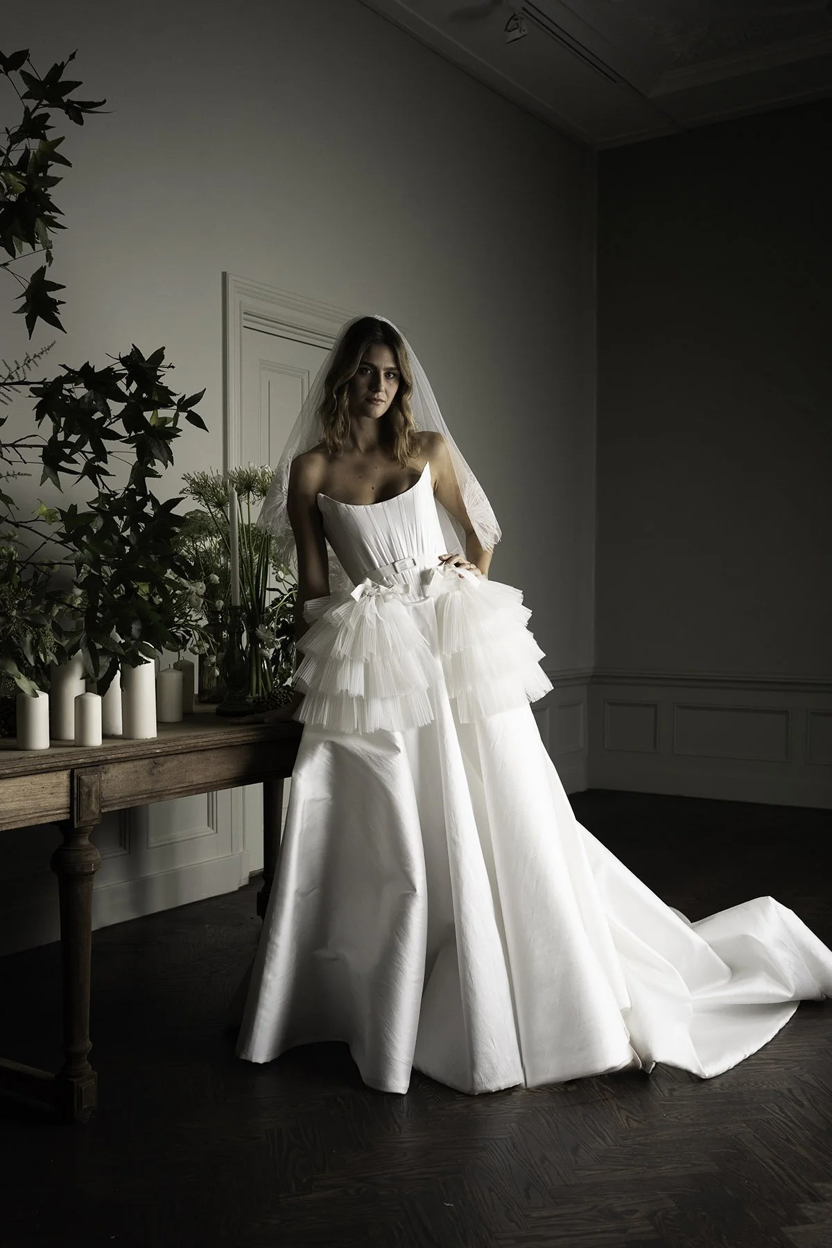 Woman wears a white mikado wedding dress with bows and tulle ruffles by Edwin Oudshoorn