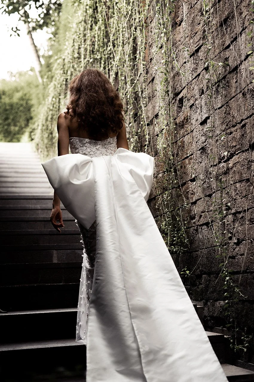 Woman wearing column wedding gown in beaded lace with oversized bow at back "Marlow" by Atelier Edwin Oudshoorn