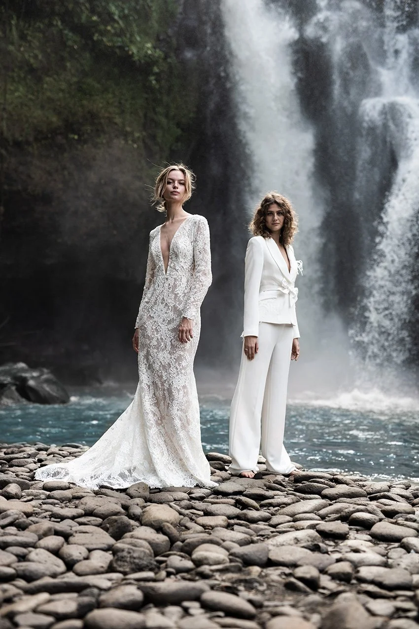Woman wearing white crepe 2 piece suit with embroidery "Emma" and woman wearing ffull lace wedding gown "Harper" by Atelier Edwin Oudshoorn