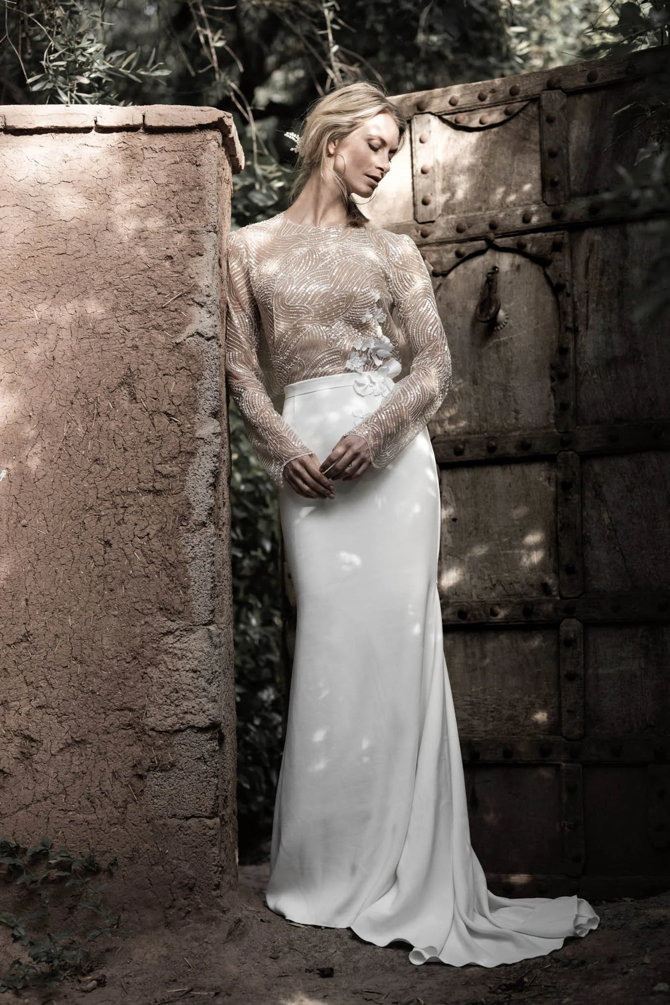 Bride wears wedding dress with embroidered tulle top with open back and crepe fishtail skirt, posing in Marrakech