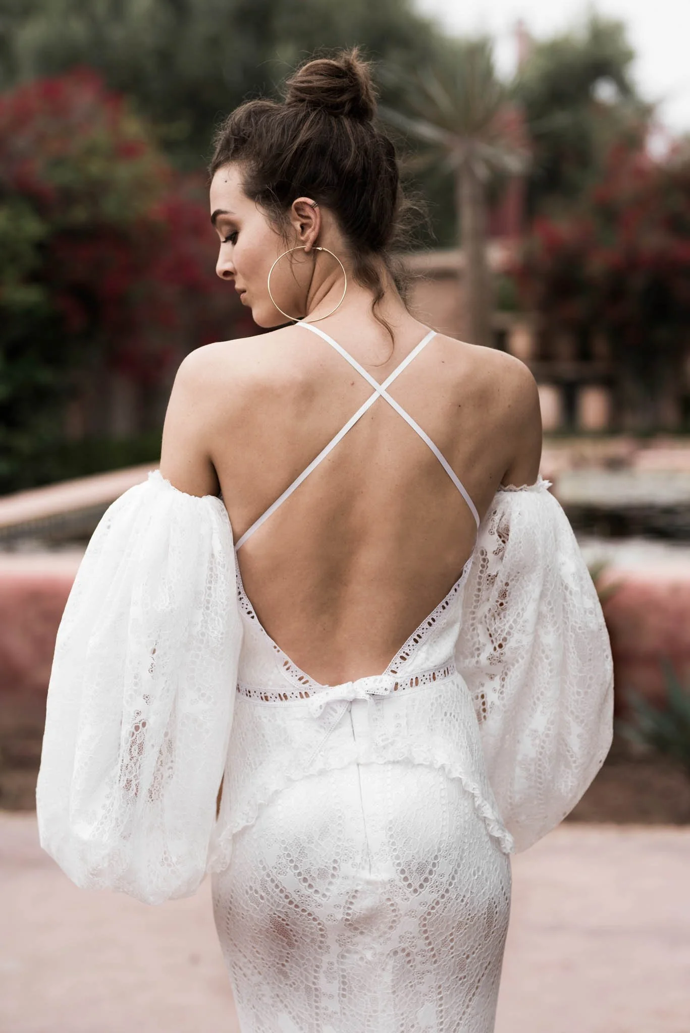 Bride wears fitted lace wedding gown with oversized puff sleeves from designer Edwin Oudshoorn in a garden in Marrakech