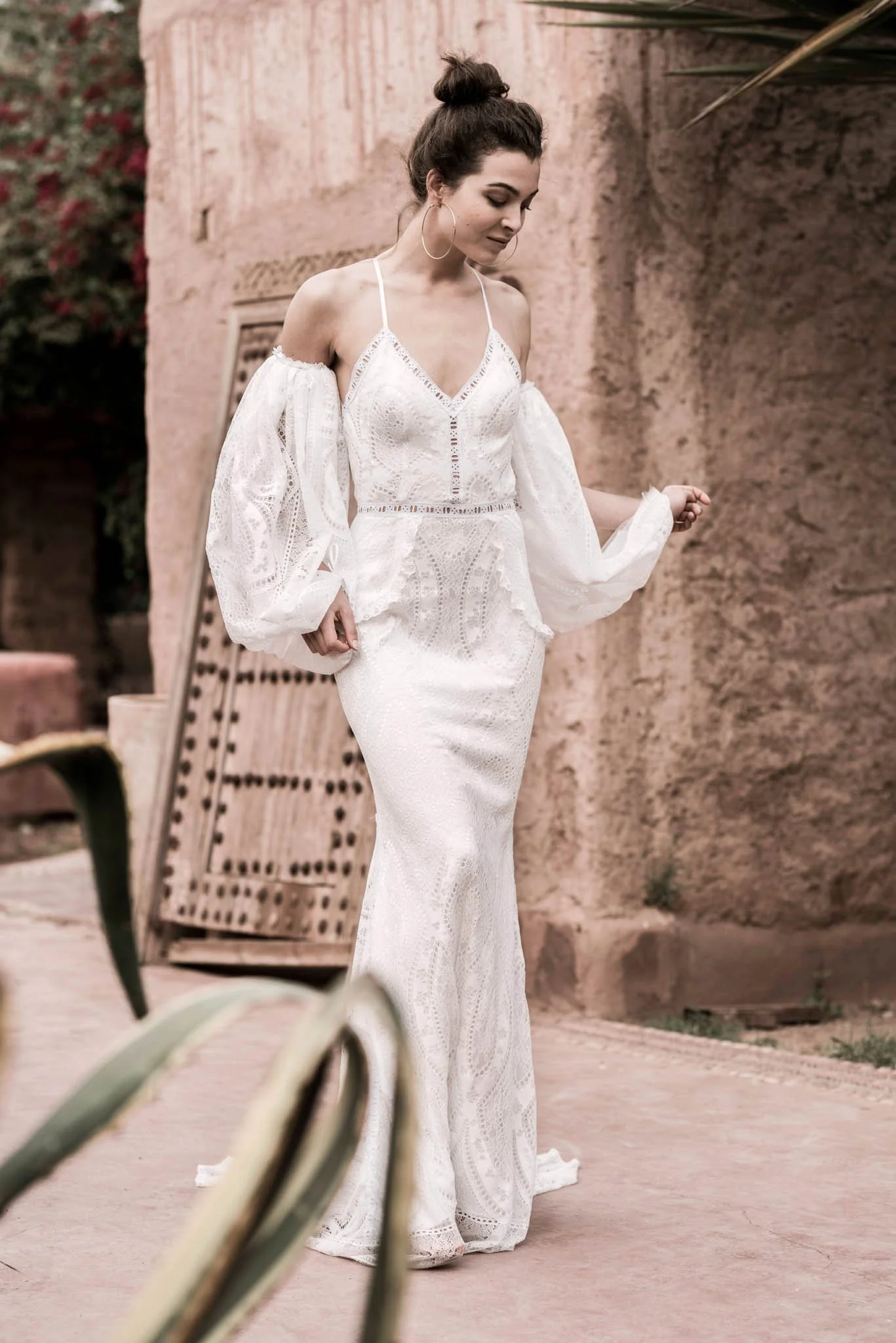 Bride wears fitted lace wedding gown with oversized puff sleeves from designer Edwin Oudshoorn in a garden in Marrakech