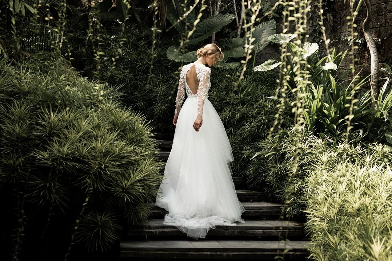 Woman in HighLow wedding gown with tulle skirt and embroidered top with long sleeves "Noor" by Atelier Edwin Oudshoorn