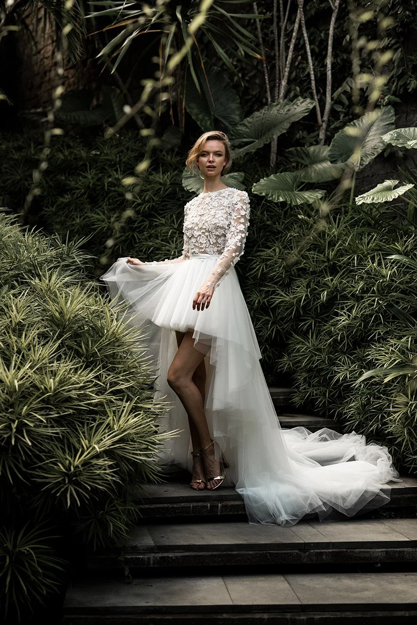 Woman in HighLow wedding gown with tulle skirt and embroidered top with long sleeves "Noor" by Atelier Edwin Oudshoorn