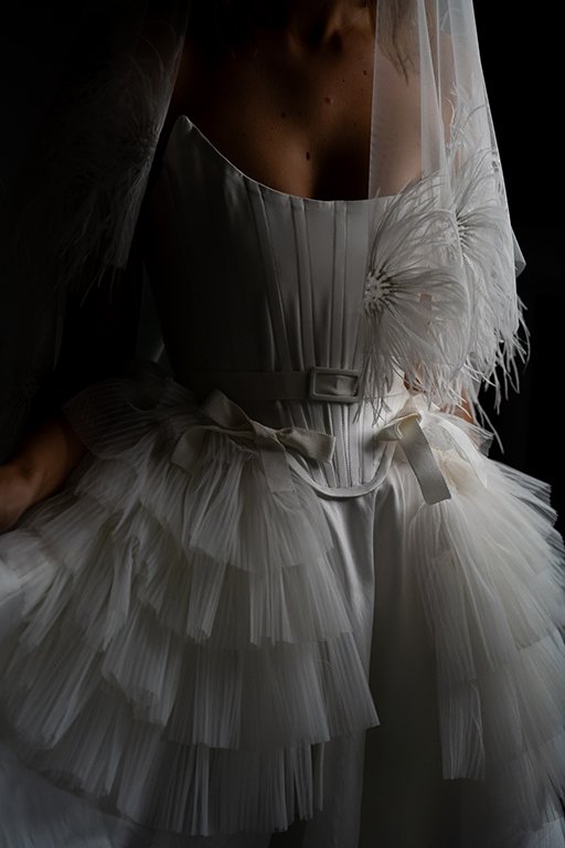 Woman wears a white mikado wedding dress with bows and tulle ruffles by Edwin Oudshoorn