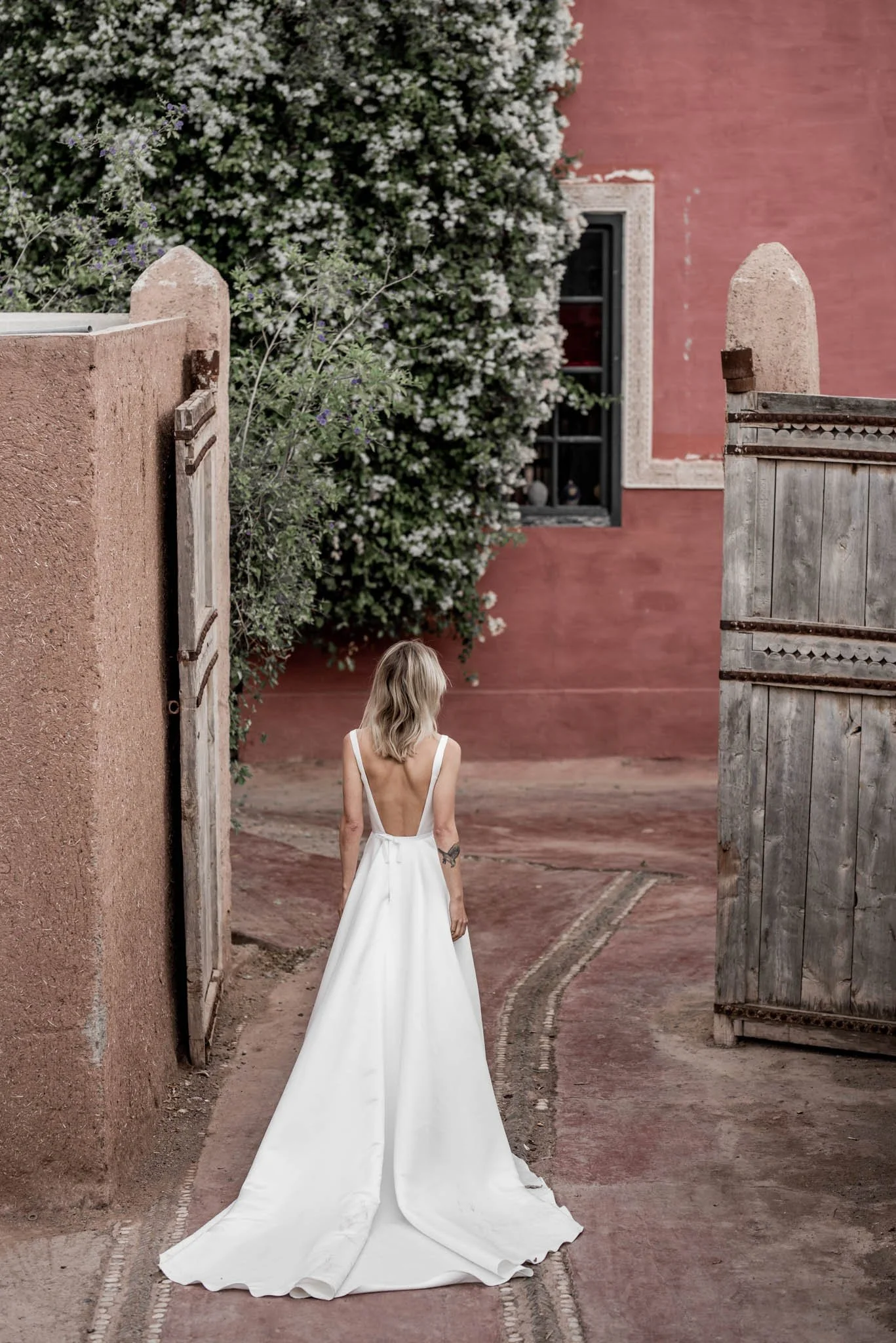 Model wears Satin wedding gown with modest neckline and long train