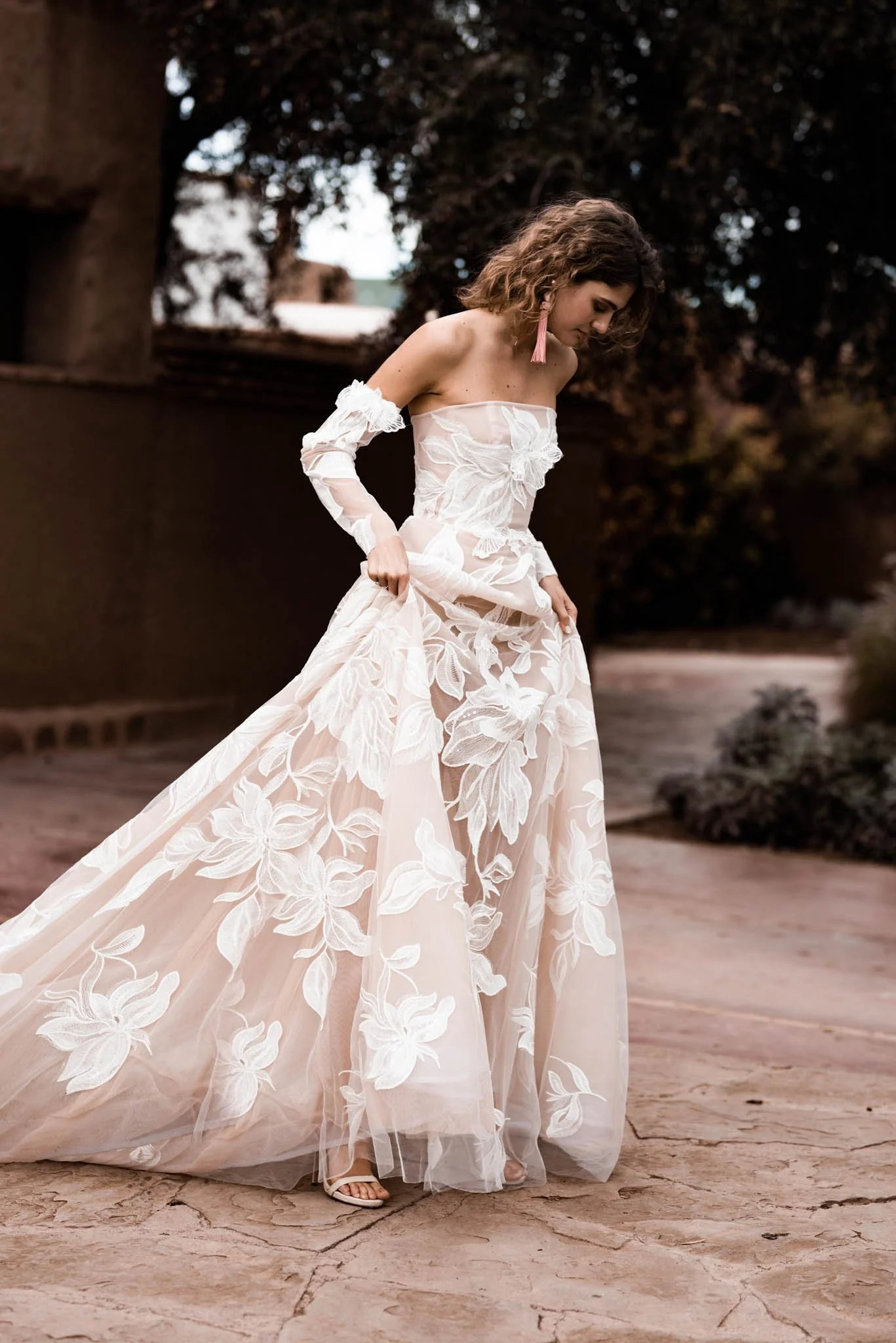 Bride wearing a blush wedding gown with long sleeves  with Iovry lace with large flower pattern and long train "Paige" by Atelier Edwin Oudshoorn