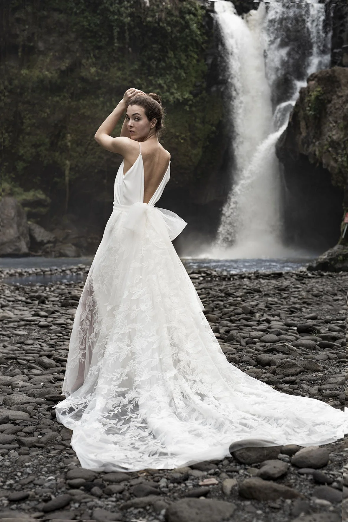 Woman wearing a white embroidered tulle bridal skirt by a waterfall in bali