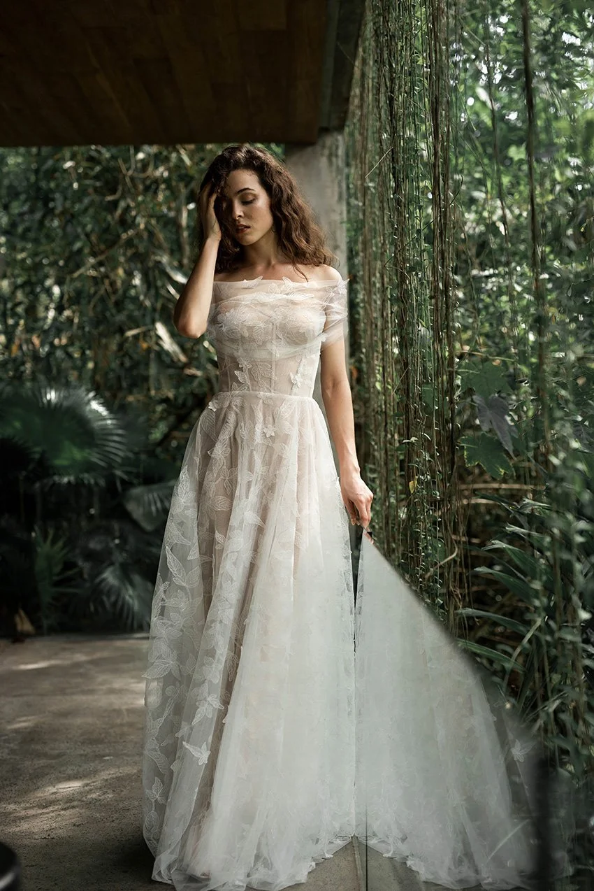 Bride wears lace wedding dress featuring embroidered leaves on a custom corset with visible boning